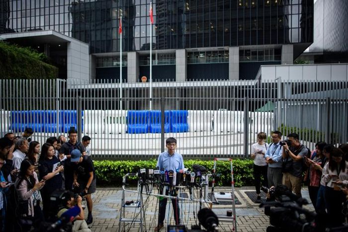 Pro-democracy activist Joshua Wong speaks to the media outside the Legislative Council in Hong Kong after learning he had been barred from standing in upcoming local elections