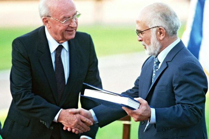 Jordan's King Hussein (R) and Israeli Premier Yitzhak Rabin shake hands after exchanging the documents of the peace treaty on the southern shore of the Sea of Galilee