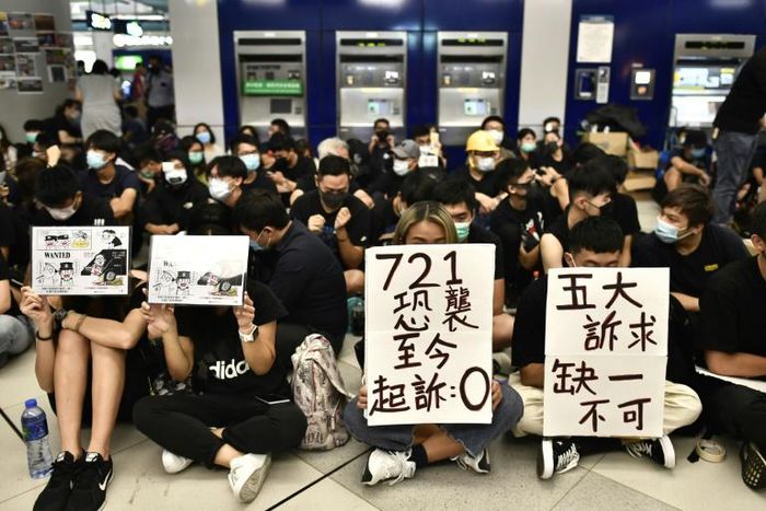Protesters hold placards during a sit-in at Yuen Long MTR station in Hong Kong