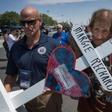 Antonio Basco (R) holds the cross of his common-law wife Margie Reckard who died in the El Paso shooting, as he walks to a makeshift memorial after the shooting that left 22 people dead