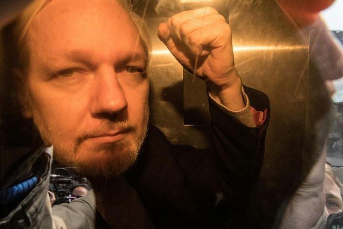 WikiLeaks founder Julian Assange gestures from a police van in May. He has now been ordered to appear in court in person for a hearing on October 21. violation.