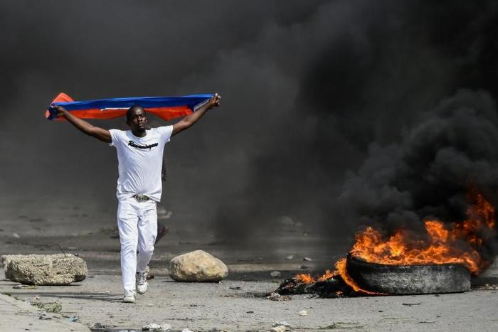 A demonstrator waves a Haitian flag during a protest against President Jovenel Moise on October 4, 2019 in Port-au-Prince