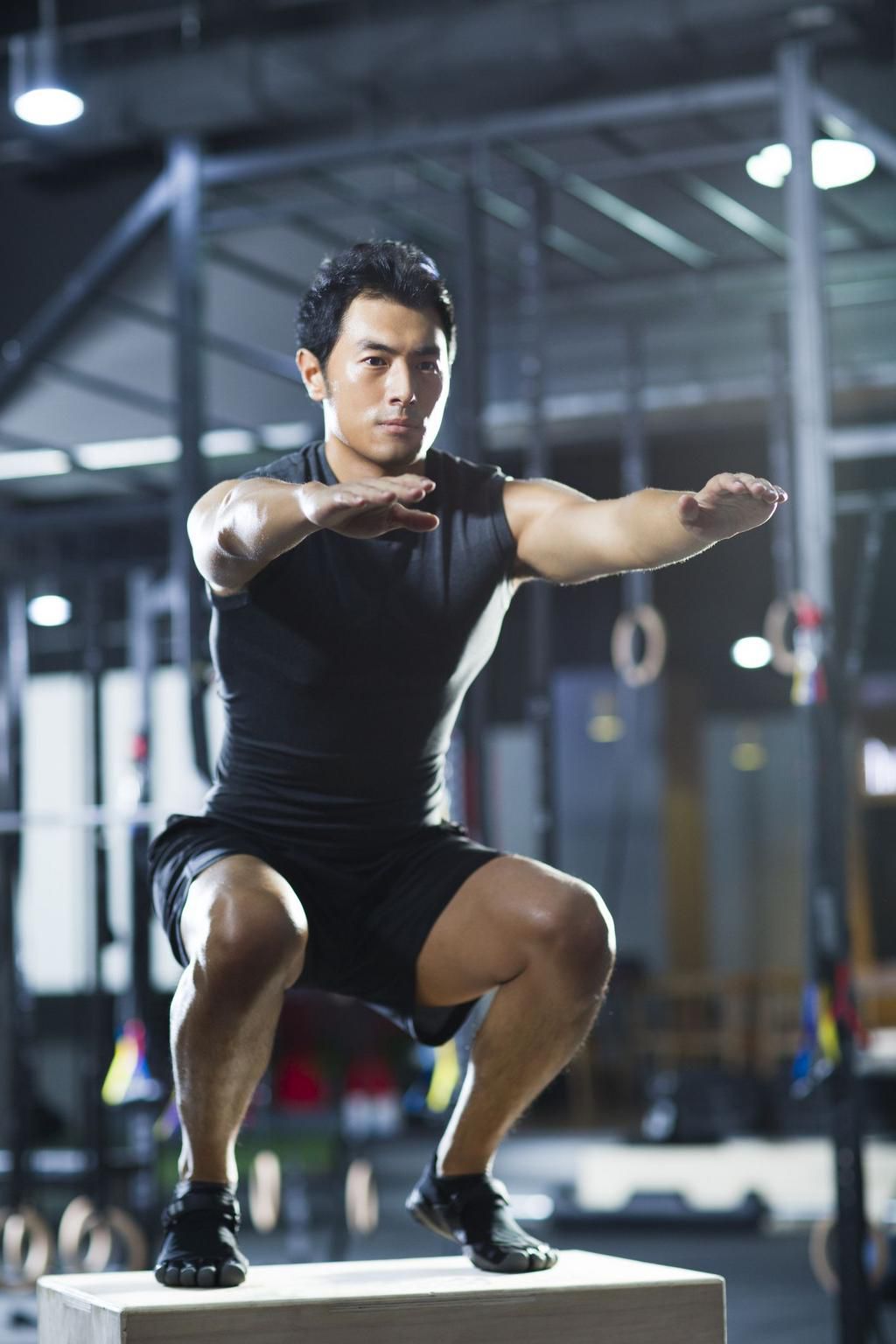 Young man doing box jump in gym gym