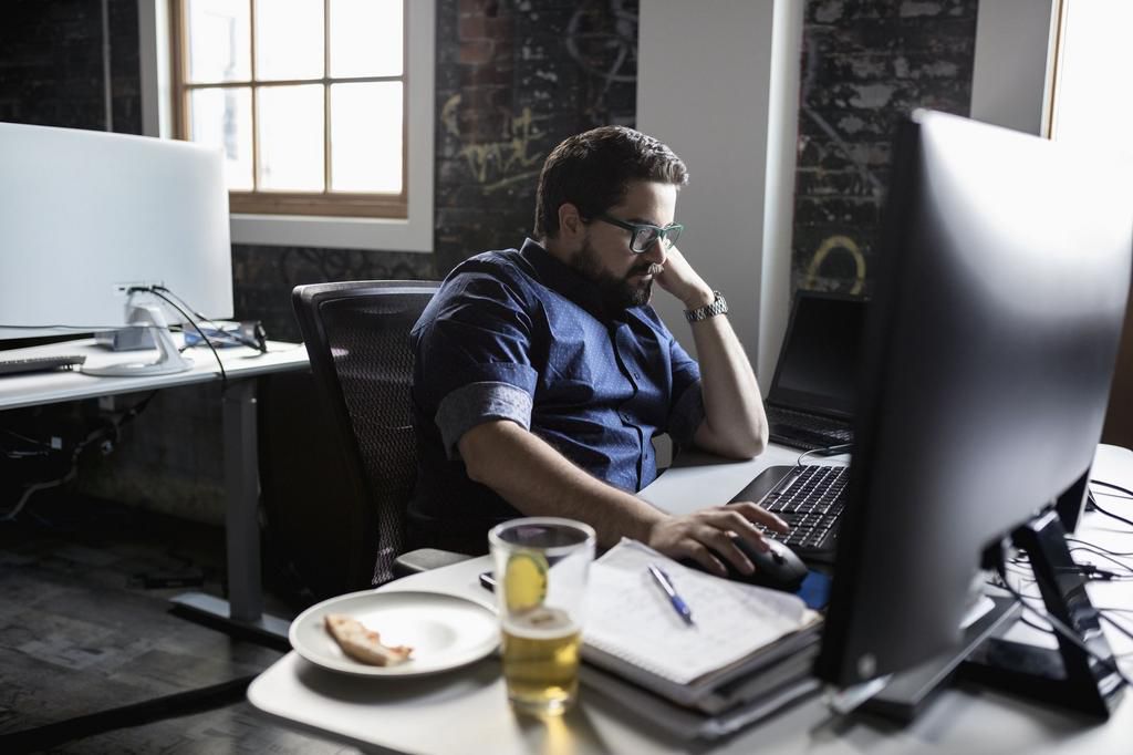 Creative businessman working and eating pizza and drinking beer at desk