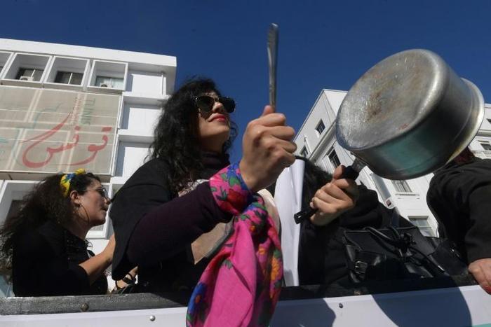 A member of the Tunisian "EnaZeda", (Me too) movement bangs a pot at a rally against sexual harassment in Tunis on November 30, 2019