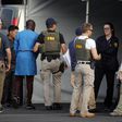 Federal agents hold a detainee, second from left, at a downtown Los Angeles parking lot after predawn raids that saw dozens of people arrested in the L.A. area on Thursday, Aug. 22, 2019 [AP Photo/Reed Saxon]