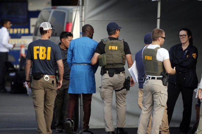 Federal agents hold a detainee, second from left, at a downtown Los Angeles parking lot after predawn raids that saw dozens of people arrested in the L.A. area on Thursday, Aug. 22, 2019 [AP Photo/Reed Saxon]