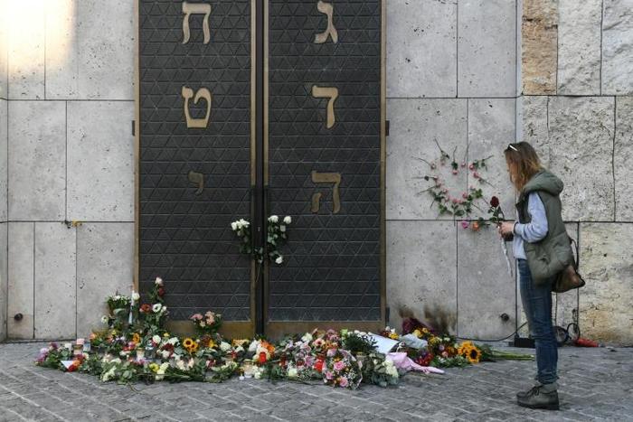 A woman stands next to flowers laid next to the entrance of the synagogue in Munich, dring a protest against anti-Semitism on October 11, 2019 two days after a deadly shooting during an attack in Halle targeting a Turkish restaurant after an attempt at...