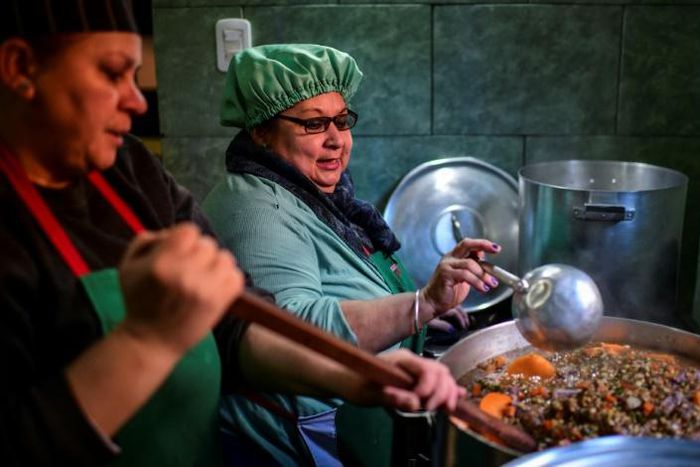 Women serve food at a soup kitchen which feeds at least 200 people hit hard by the economic crisis