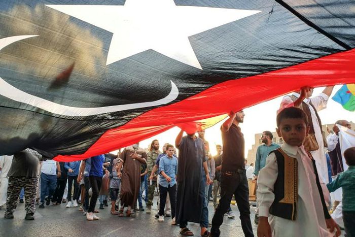 Libyans march in Tripoli with a giant national flag during a September demonstration in support of the UN-recognised government and against strongman Khalifa Haftar who has led an offensive on the capital city since April