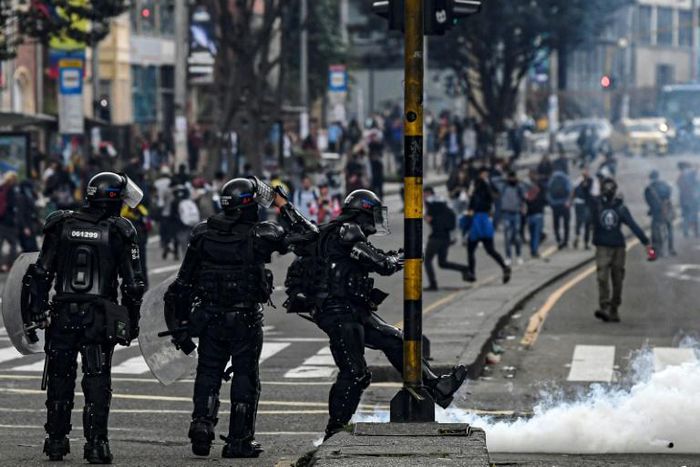 A riot policeman kicks a tear-gas canister during an anti-government protest in Bogota on November 23, 2019