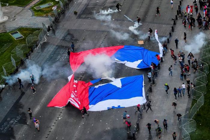 Demonstrators in Santiago carried a torn Chilean flag on October 25, 2019, as sometimes violent protests over both political and economic demands showed little sign of abating