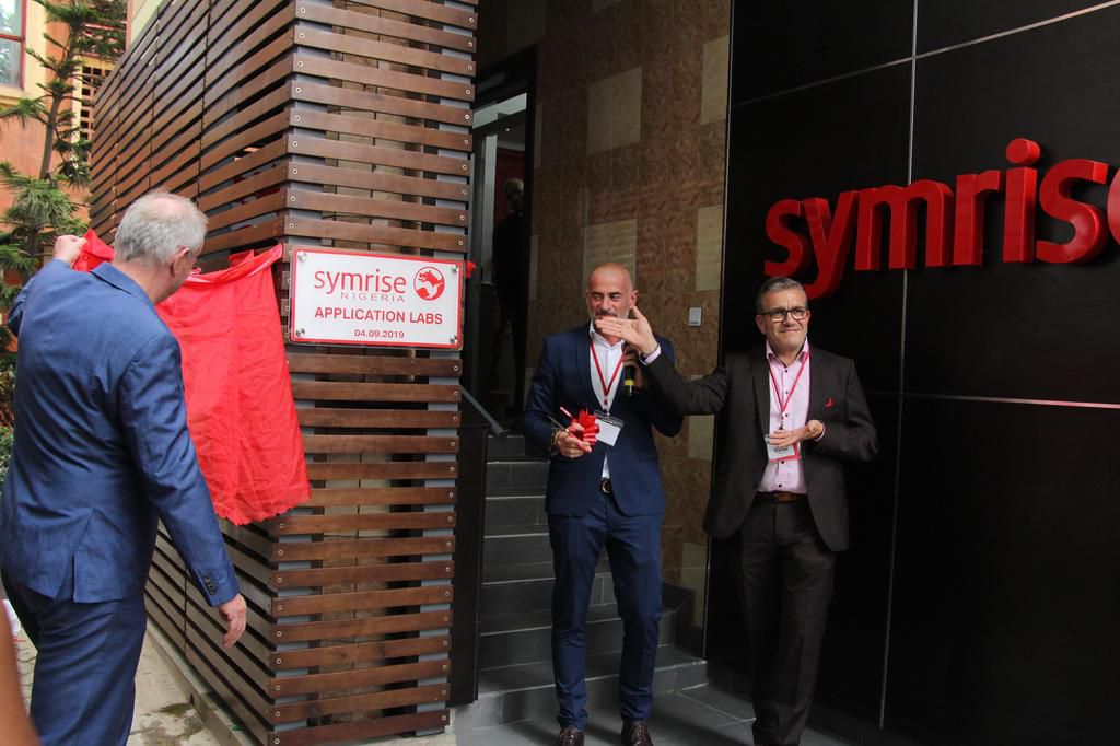 Thomas Dressler, President EAME Fragrances and Oral care, Alexander Lichter, Vice President Flavour Sales EAME and Daniel Ibarra, Vice President EAME Cosmetic Ingredients Division reveal the signage at the official opening of Symrise Application Labora...
