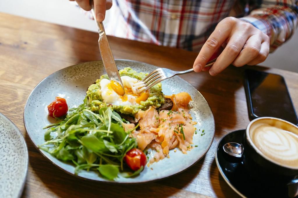 Man eating avocado toast with egg, salmon and arugula salad for brunch at the restaurant