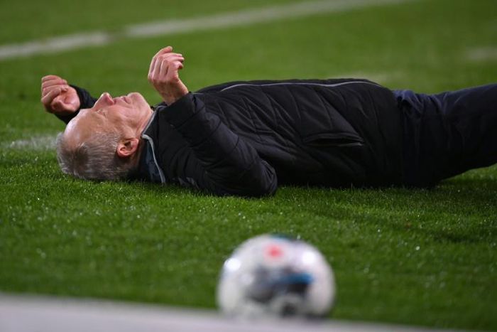Freiburg head coach Christian Streich lies on the pitch after being barged by Frankfurt captain David Abraham on Sunday.
