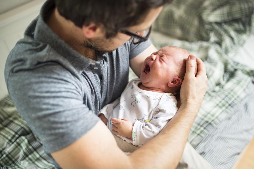 Father at home consoling his crying baby daughter