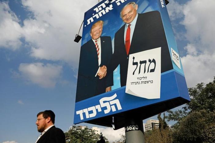 An Isreaeli man walks past an election billboard for the Likud party, showing US President Donald Trump (L) shaking hands with Prime Minister Benjamin Netanyahu in Jerusalem: Trump said Israel's latest election will be "50/50"
