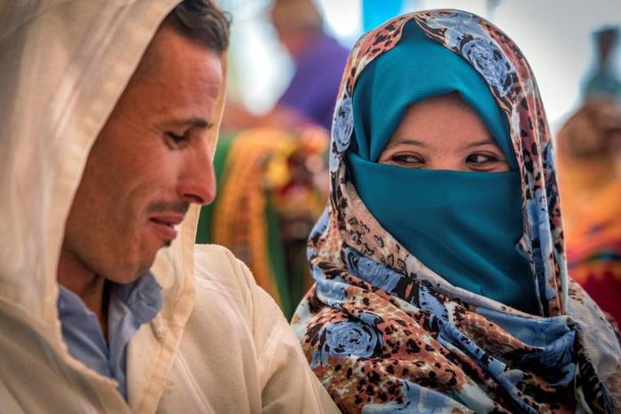 A young Amazigh couple smile at each other as they wait for their turn at a group wedding in Morocco's Atlas mountains