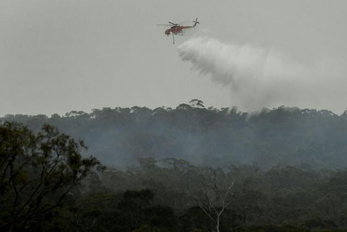 A helicopter dumps water on a bushfire in the outer suburbs of Melbourne