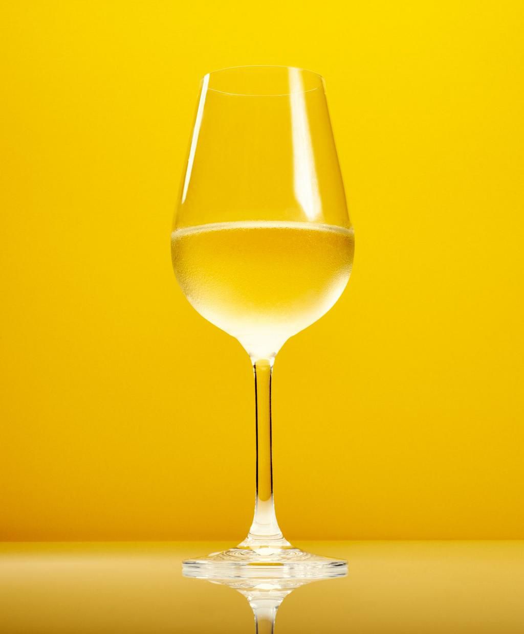 Close-Up Of White Wine Against Yellow Background
