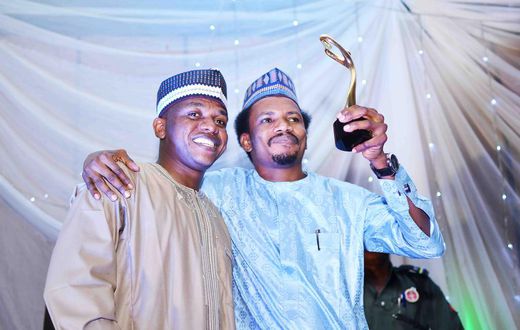 Senator Elisha Abbo (right) raises his "Beacon of Hope" award. "Beacon of Hope" was his campaign slogan before he was elected as the youngest senator in the 9th Senate. Weeks before his inauguration, he beat up and arrested a woman for telling him to c...