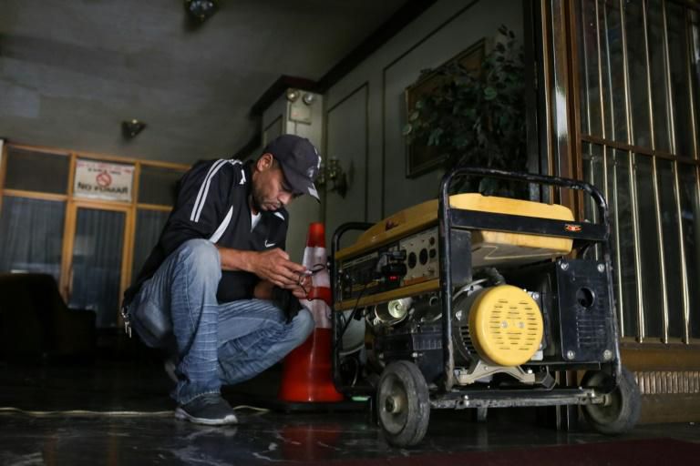 A man connects his cellphone to a power generator during the power outage in Caracas