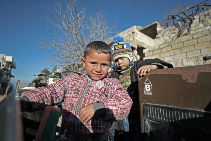 Children stand in the back of a truck as their father, Abu Ismail, prepares to evacuate them from the jihadist-held town of Maaret al-Numan in Syria's Idlib province