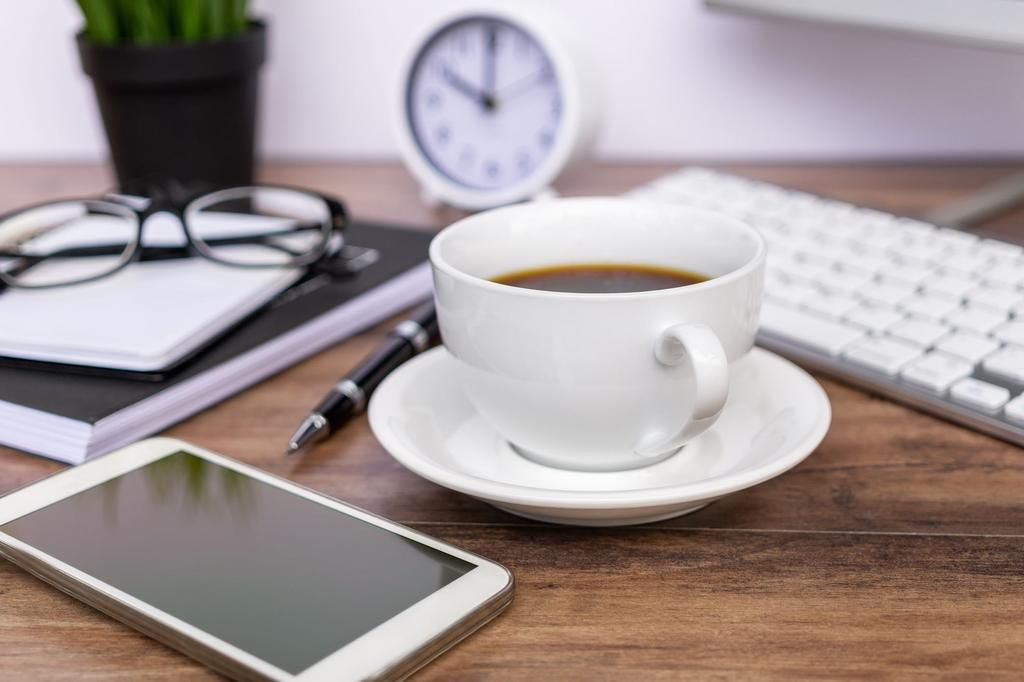 Smart Phone and Cup of Coffee on Top of Office Desk.