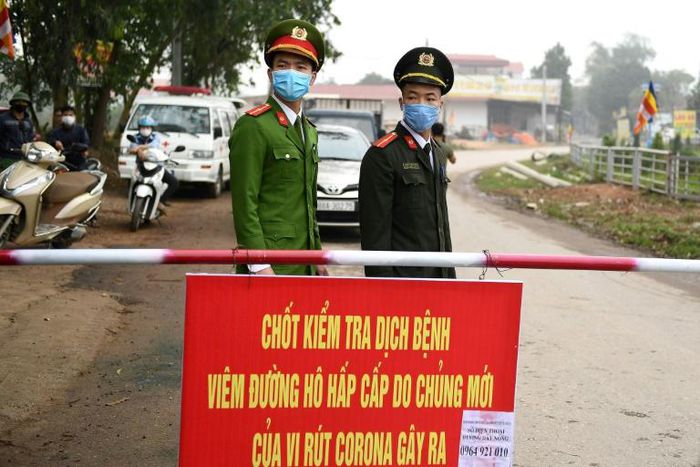 Vietnamese police stand guard at a checkpoint set up at the Son Loi commune in Vinh Phuc province amid concerns about a COVID-19 coronavirus outbreak