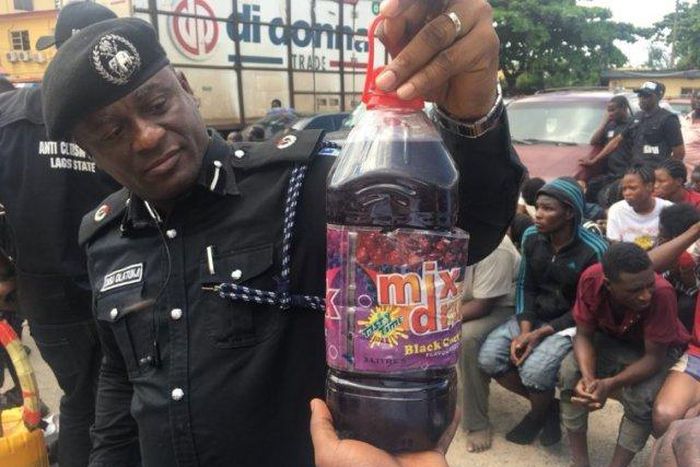 An illustrative photo of a police officer displaying a bottle containing skuchies drink. [gpowerradio]