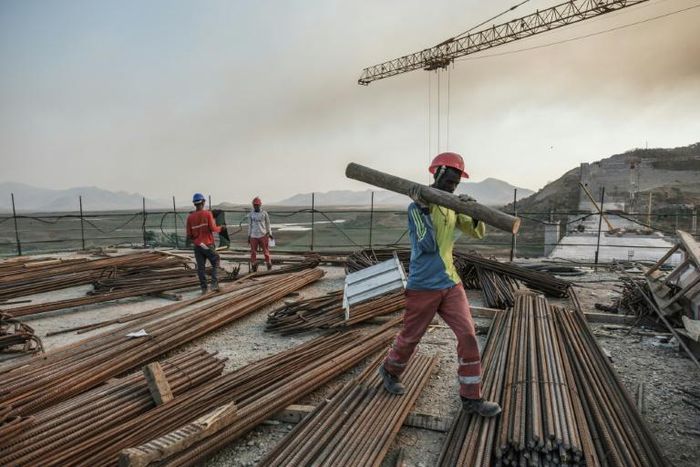 A worker walks with a piece of wood on his shoulder at the Grand Renaissance Dam, near Guba in Ethiopia