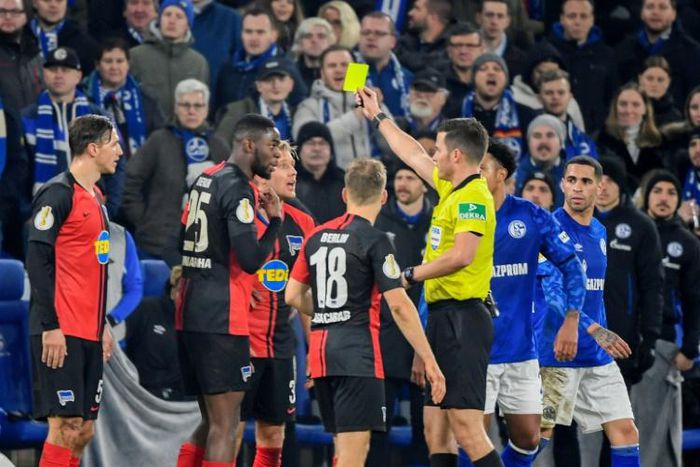 Hertha Berlin defender Jordan Torunarigha (2ndL) is booked for the second time during Tuesday's German Cup, third round match against Schalke in Gelsenkirchen