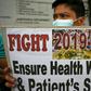 A health worker wearing a face mask holds a placard during a protest in front of a government hospital in Manila