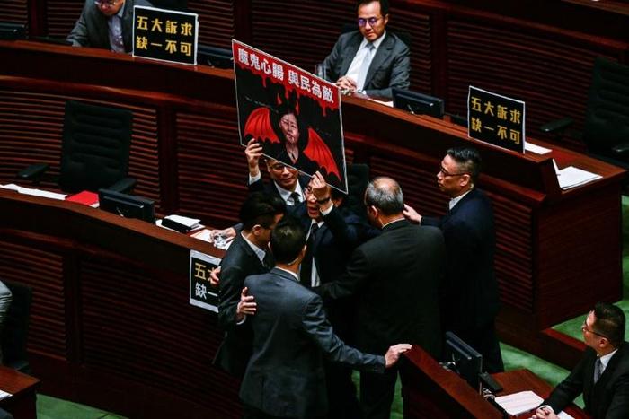 Security officials were called in to force out pro-democracy lawmakers who shouted slogans and held placards criticising Hong Kong's leader Carrie Lam