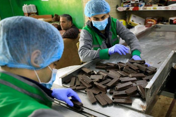 Workers at al-Arees sweets factory in Gaza City sort a batch of chocolate-covered biscuits