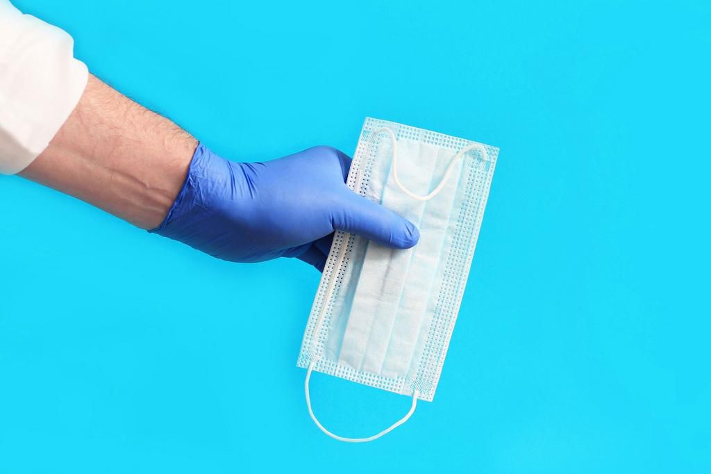 hand holding a medical mask, hand in blue glove