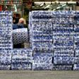 A woman wearing a protective face mask walks past stacks of toilet paper for sale in the Tsuen Wan district of Hong Kong