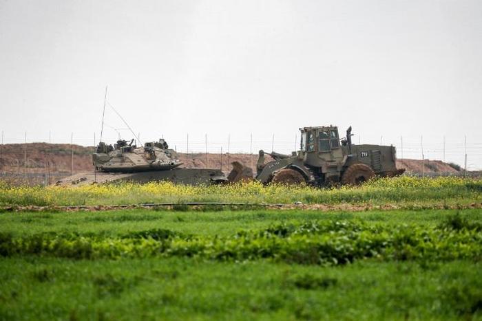 An Israeli tank and a bulldozer are seen along the border fence between Israel and the Gaza Strip where the army says troops shot dead a Palestinian suspected of placing a bomb near the barrier