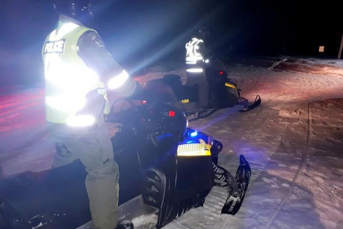 Police use snowmoblies during a search and rescue operations after a Canadian guide died and five French tourists went missing when their snowmobiles plunged through ice into the freezing water