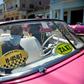 Workers of a private taxi company disinfect old American cars wearing face masks as a preventive measure against the spread of the new coronavirus