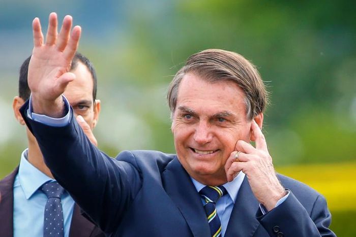 Brazilian President Jair Bolsonaro waves as he arrives for the hoisting of the national flag ceremony outside the Alvorada Palace in Brasilia, on January 21, 2020