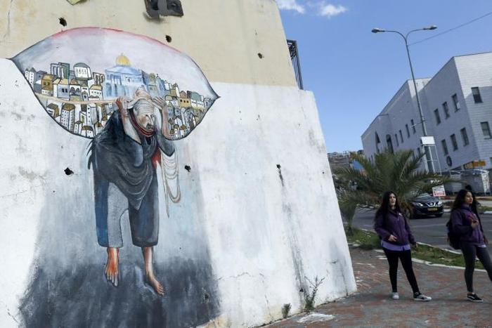 Schoolgirls walk past a mural in the Arab-Israeli town of Umm al-Fahm north of Tel Aviv