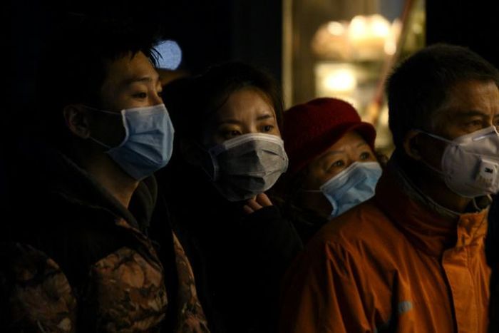 People wearing protective facemasks queue for food in Shanghai
