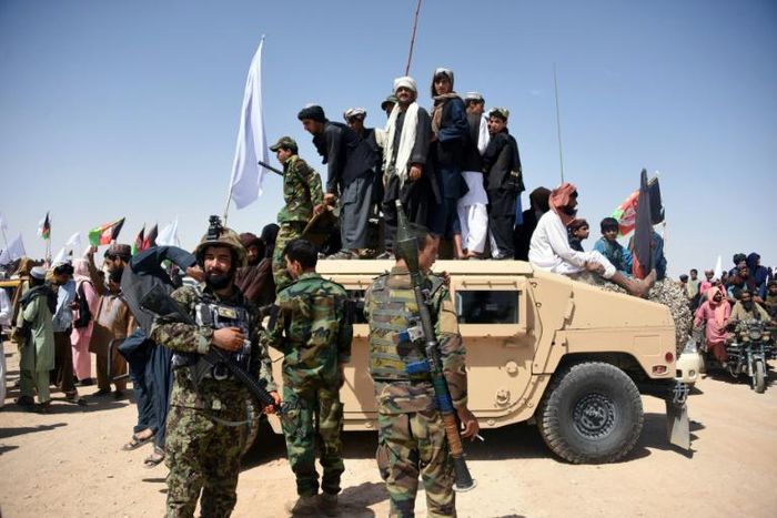 Afghan Taliban militants and residents stand on an Afghan National Army armoured Humvee as they celebrate a ceasefire in Kandahar province