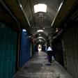 A woman walks past closed shops along a deserted alley in the Old City of Jerusalem