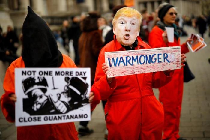 A protester holds up a placard, dressed as US President Donald Trump in Trafalgar Square during a demonstration against the threat of war on Iran, in central London on January 11, 2020