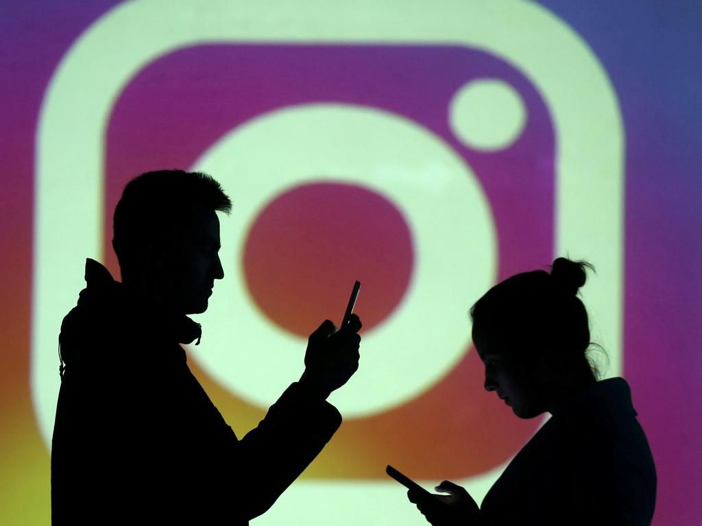 FILE PHOTO: Silhouettes of mobile users are seen next to a screen projection of Instagram logo in this picture illustration taken March 28, 2018.  REUTERS/Dado Ruvic/Illustration/File Photo