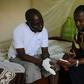 Father Guy-Robert Mandro, shown with a visitor to his home as he recovers from his maiming