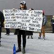 An anti-lockdown protester holds placards on the steps of Victoria's state parliament in Melbourne