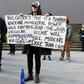 An anti-lockdown protester holds placards on the steps of Victoria's state parliament in Melbourne